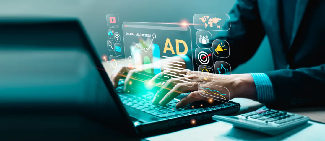 Hands on a laptop with digital marketing and ad icons floating above the keyboard
